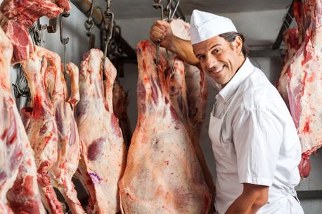 carnicero sonriente muestra piezas de carne